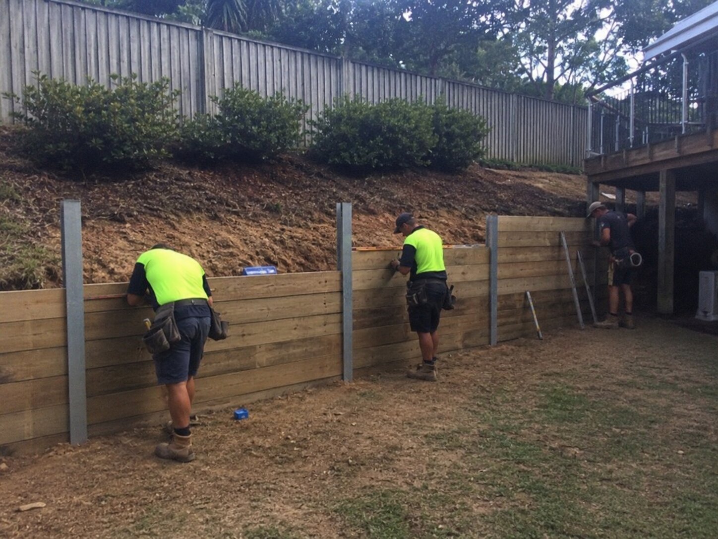 Finished split-level residential yard with concrete sleeper retaining walls and fencing