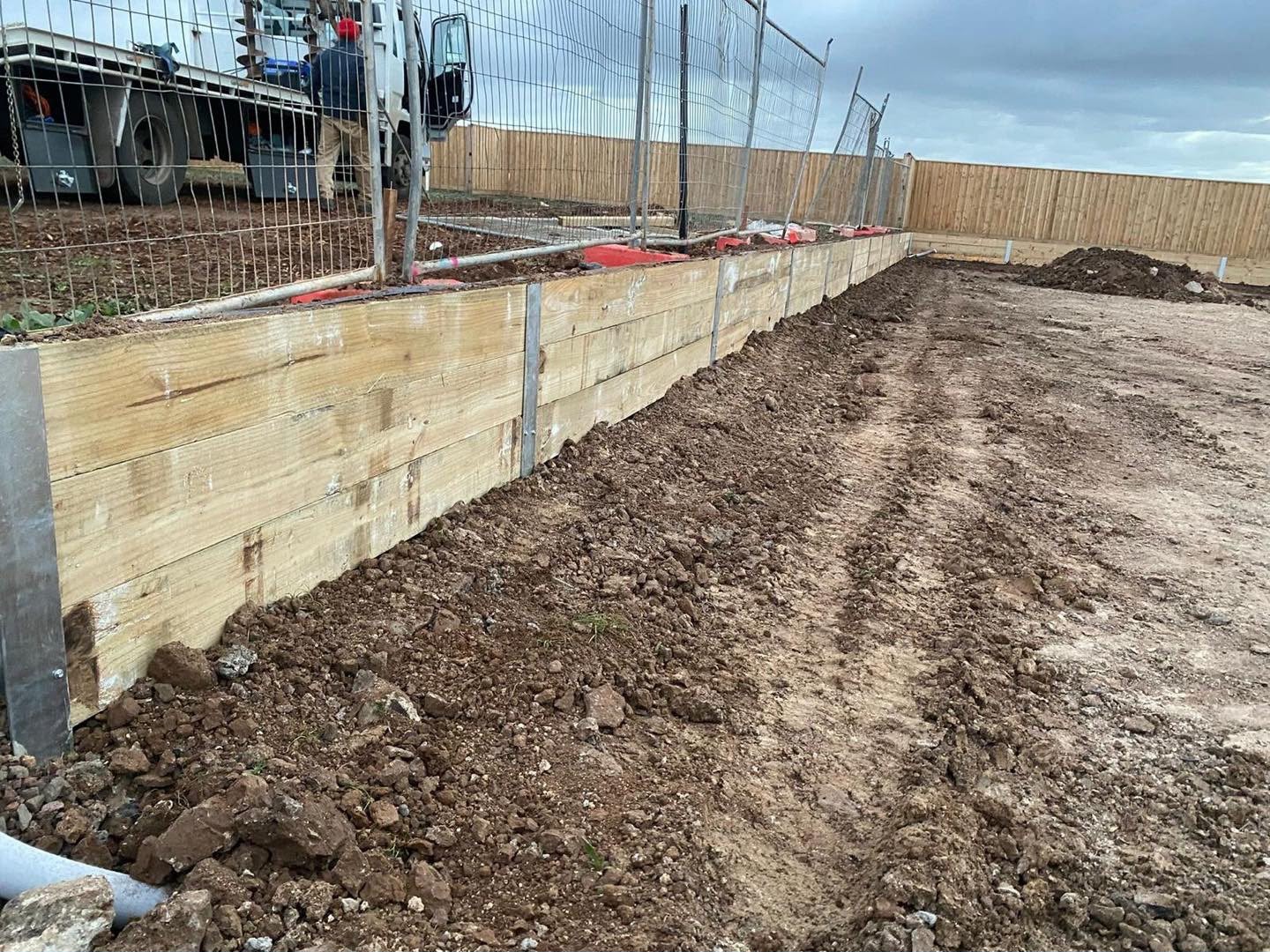 Completed timber retaining wall with native garden planting and gravel path in morning light