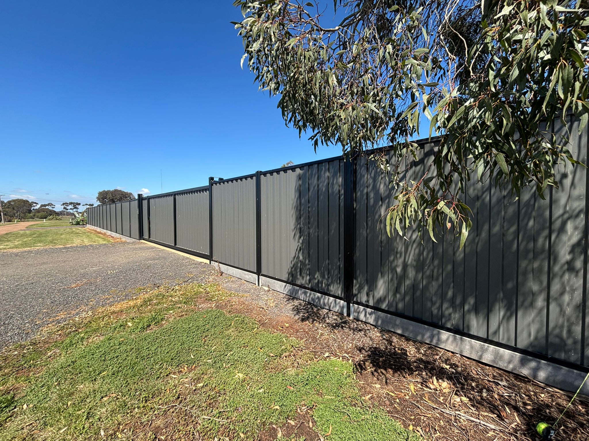 Completed multi-tiered concrete retaining wall at golden hour with timber fencing